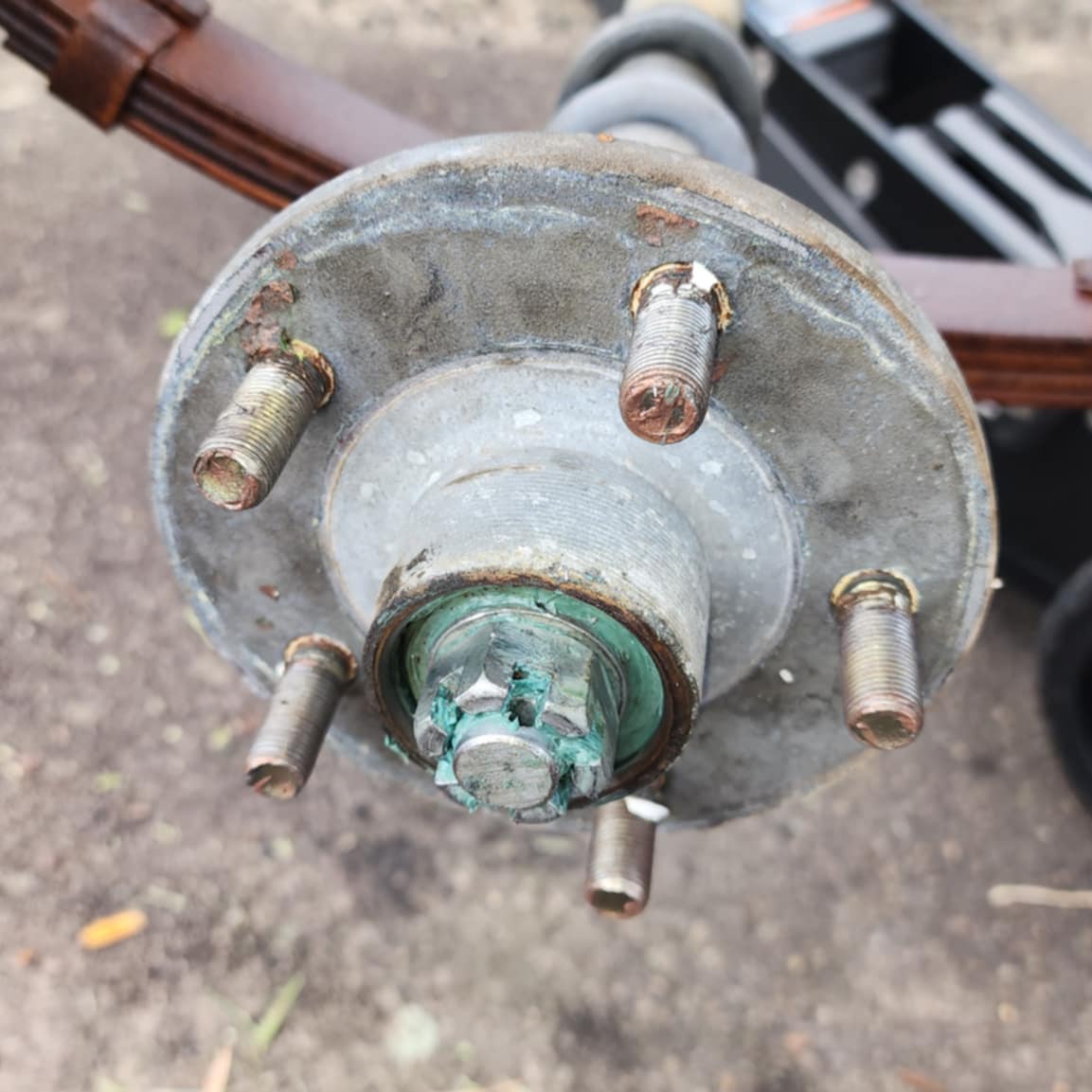 A trailer wheel hub with the bearing cap off, studs and hub nut exposed