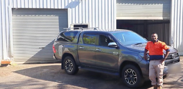 Marco standing beside his grey Toyota HiLux work ute outside the workshop